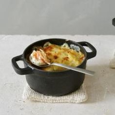 two black pots with food in them on a white tablecloth next to each other