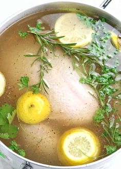 a pot filled with chicken and lemons on top of a stovetop next to some herbs