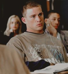 a young man listening to music while sitting in front of other people