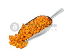 a spoon filled with yellow peas on top of a white surface