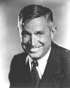 an old black and white photo of a man in a suit smiling at the camera