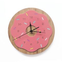 a wooden clock with a pink doughnut on it's face and colorful sprinkles