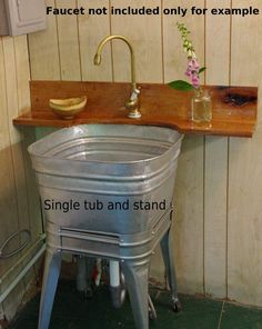 a sink with a wooden counter top next to a metal trash can and some flowers