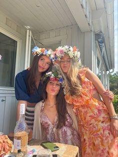 three women with flower crowns on their heads are posing for a photo at an outdoor party