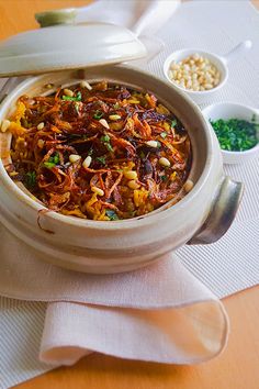 a bowl filled with food sitting on top of a table next to other bowls and spoons