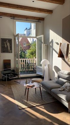 a living room with an open window and wooden floors