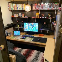 a computer desk with two monitors on top of it and shelves full of toys above