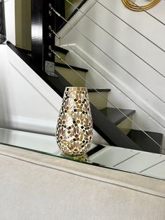 a vase sitting on top of a glass table next to a stair case and railing