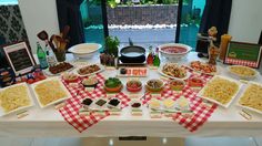 a table filled with lots of food on top of a white tablecloth covered table