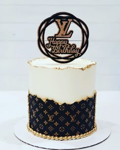 a white and black birthday cake with gold lettering on it's top, decorated with louis vuitton monograms