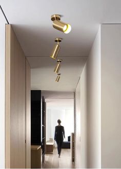 a person walking down a hallway with lights on either side of the door and ceiling