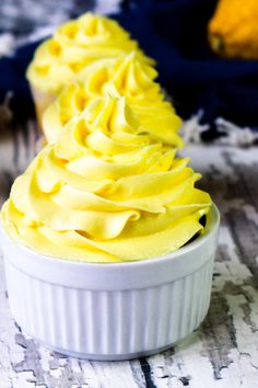 a white bowl filled with yellow frosting on top of a table