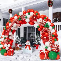 an arch made out of balloons and candy canes in front of a house decorated for christmas