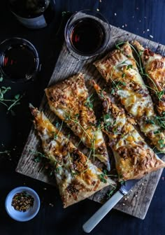 several slices of pizza sitting on top of a cutting board next to some dipping sauces