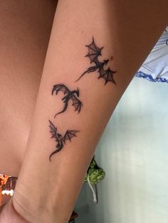 a woman with a tattoo on her arm that has two bats flying through the air