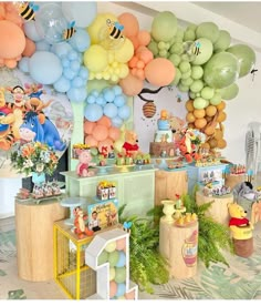 winnie the pooh birthday party with balloons, decorations and desserts on display in a room