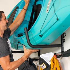 a man is holding up a blue kayak