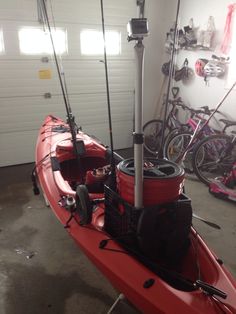 a red kayak with fishing rods and reels attached to it in a garage