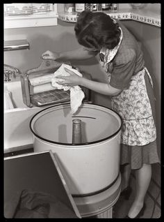 an old photo of a woman washing dishes