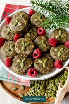 a white plate topped with cookies covered in nuts and raspberries next to green beans