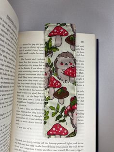 an open book with a hedge and mushrooms on it