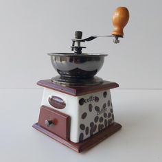 an old fashioned coffee grinder is sitting on a white counter top with a wooden handle