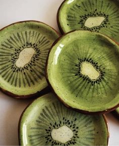 four kiwi plates with holes in them on a table