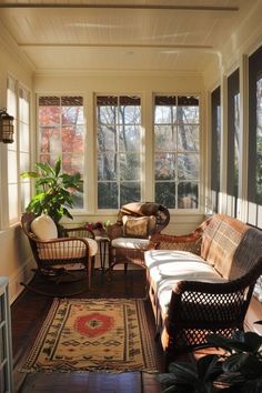 a sun room with wicker furniture and plants in the window sill, along with a rug on the floor