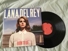 a black vinyl record sitting on top of a bed next to a red disk cover