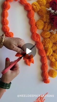 someone is doing something that looks like flowers on the wall with orange and yellow yarn