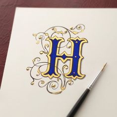 the letter h is made up of gold and blue letters on white paper with a black pen