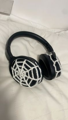 a pair of headphones with spider web design on the side, sitting on a white sheet