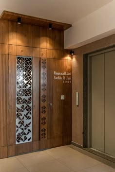 an elevator with wooden paneling and decorative glass panels on the doors, in front of a tiled floor