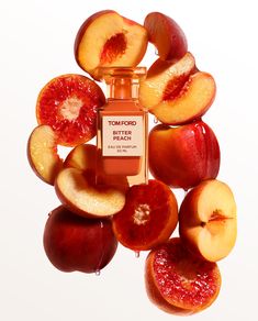 a bottle of tom ford bitter peach perfume surrounded by sliced apples and pieces of fruit