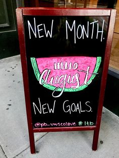 a sign that says new month into august next to a sidewalk in front of a store