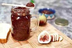 a jar filled with jam sitting on top of a cutting board next to sliced fruit