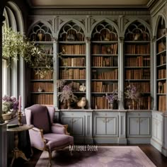 a room with many bookshelves and flowers in vases on the table next to a purple chair