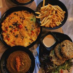 a table topped with plates of food next to french fries and burgers on top of it