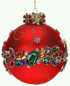 a red ball ornament with jewels and bows hanging from it's side