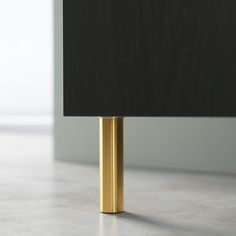 a black and gold lamp on a white floor with a gray wall in the background