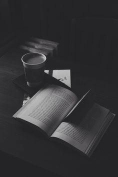 an open book sitting on top of a table next to a cup of coffee