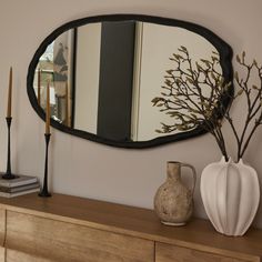 a mirror and vase on top of a dresser