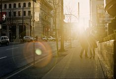 two people are walking down the street in front of tall buildings and cars on both sides