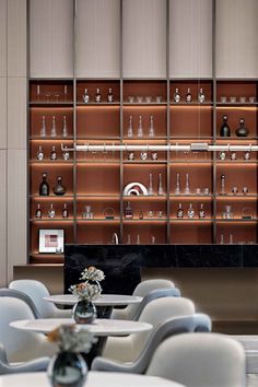 a room filled with tables and chairs next to a wall covered in shelves full of bottles