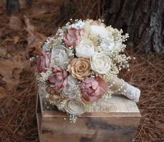 a bridal bouquet sitting on top of a wooden box next to a pine tree