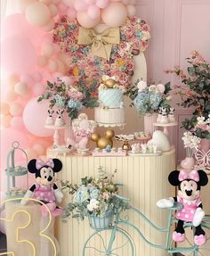 a birthday party with balloons, flowers and mickey mouse figurines on the table