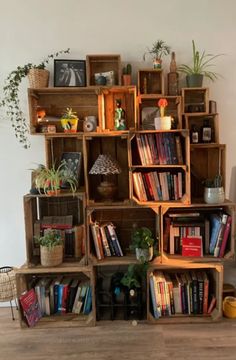 the bookshelf is made out of wooden crates and has plants on each shelf