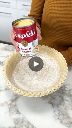 a woman holding a can of campbell's cream of chicken soup in a pie pan