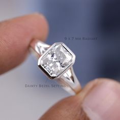 a close up of a person holding a ring with a white diamond in the middle