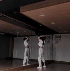 two women standing in front of mirrors with their hands on their head and arms behind them